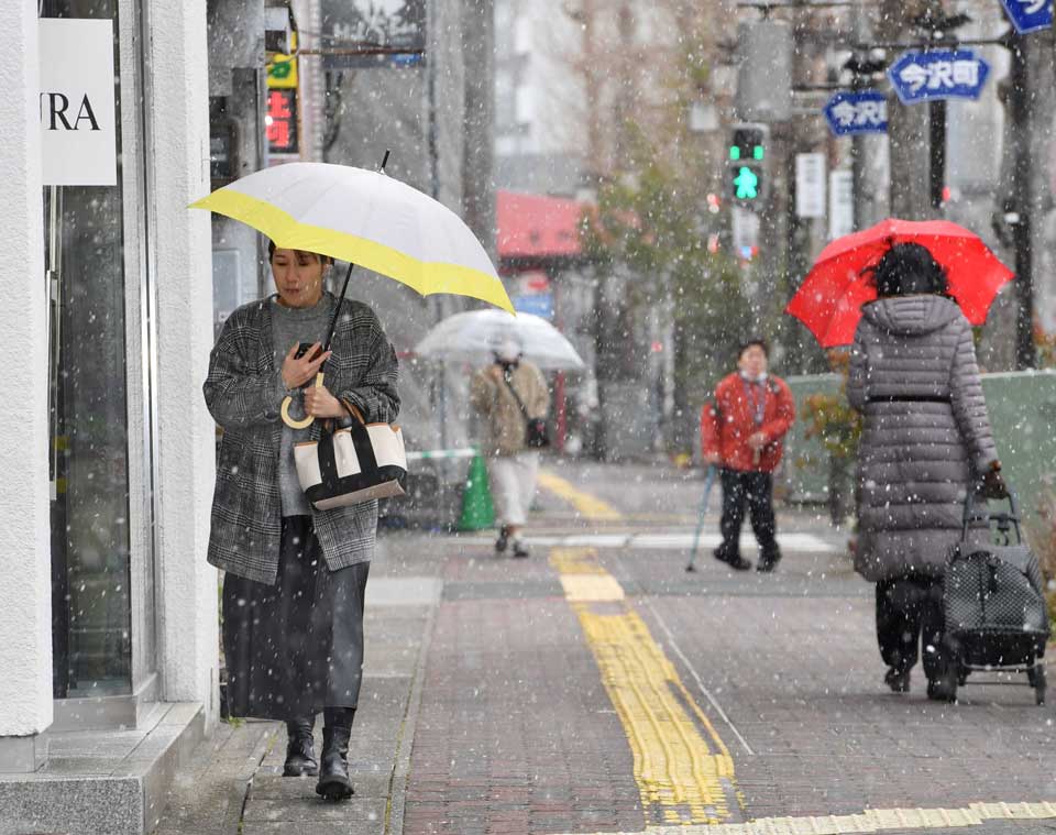 寒波が再来し雪の舞う中を歩く人たち＝岐阜市今沢町