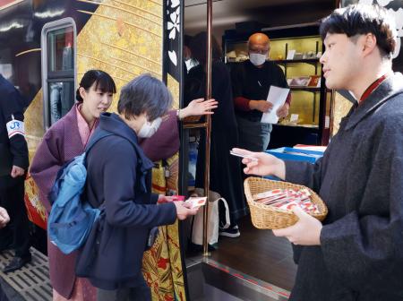 　和装したＪＲ社員らの出迎えを受け、運転を再開したＪＲ七尾線の観光列車「花嫁のれん」に乗り込む利用客＝７日午前、金沢駅