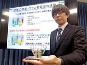 　ウラン蓄電池の模型を手にする日本原子力研究開発機構の担当者＝１３日午後、文科省