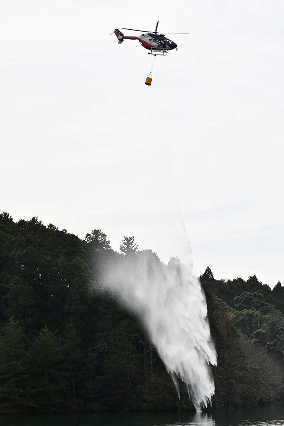 上空から山すそに向かって放水する県防災ヘリ＝同